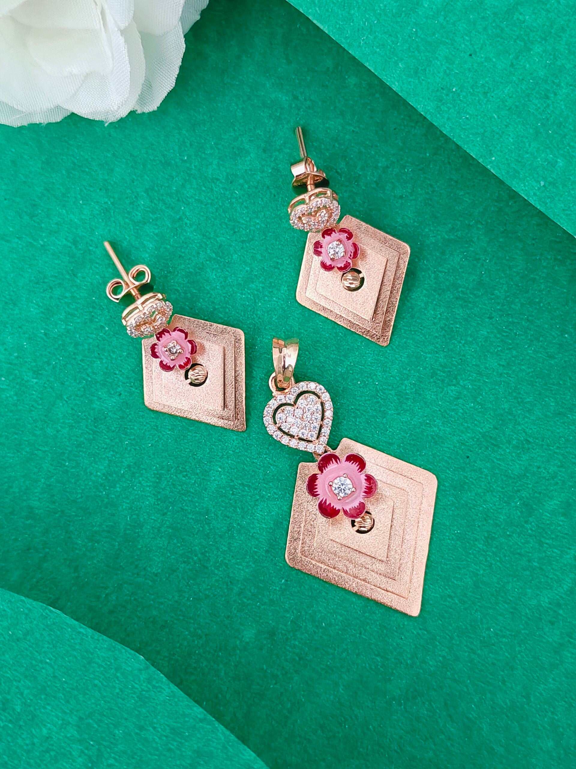 Jewelry set with square pendants and floral designs on a green surface